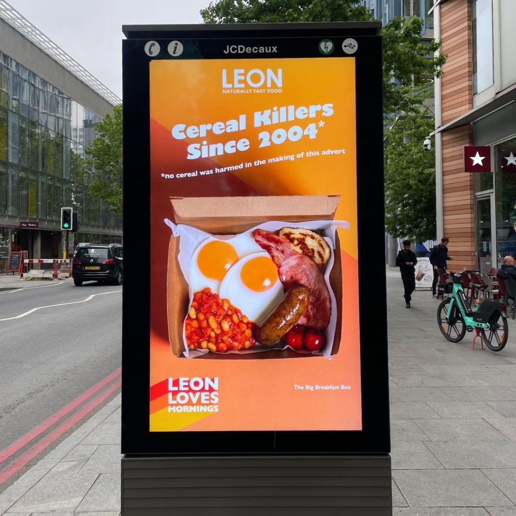 A digital billboard depicting an advertisement for LEON breakfast with the tag line 'cereal killers since 2004'